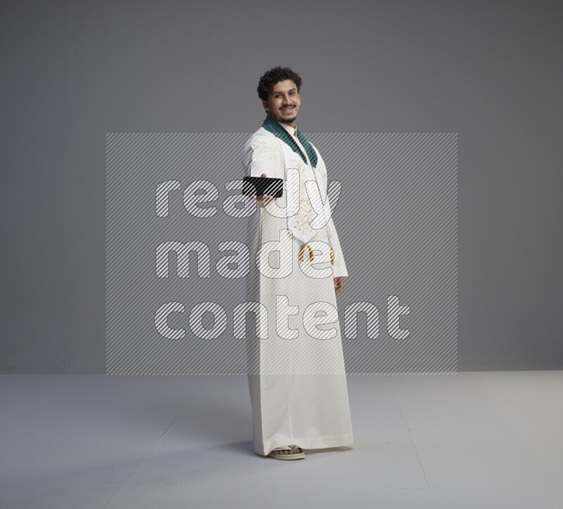 رجل سعودي يرتدي ثوب ابيض و شال يحمل جوال