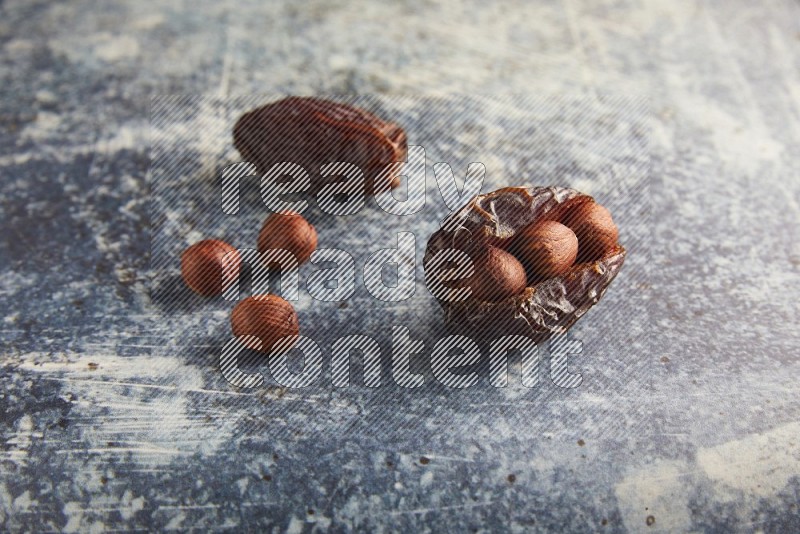 two hazelnuts stuffed madjoul dates on a rustic blue background