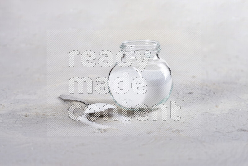 A glass jar full of fine table salt on white background