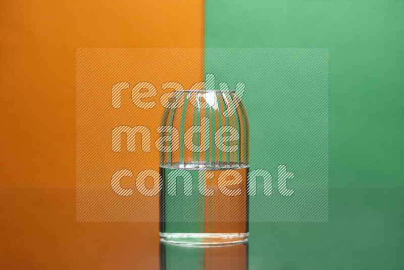 The image features a clear glassware filled with water, set against orange and green background