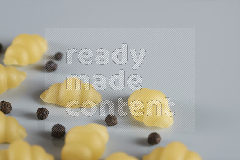 Raw pasta with different ingredients such as cherry tomatoes, garlic, onions, red chilis, black pepper, white pepper, bay laurel leaves, rosemary, cardamom and mushrooms on light blue background