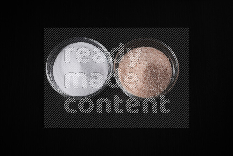 2 glass bowls one is filled with himalayan salt and the other with white salt on black background