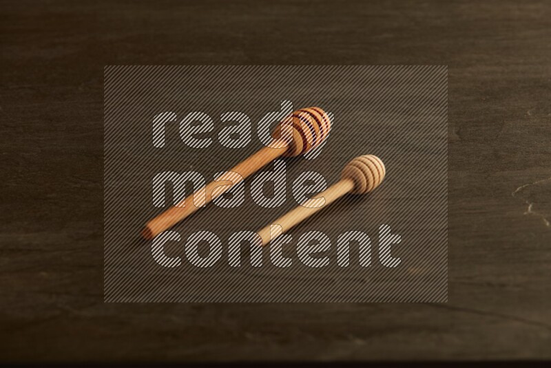 Wooden honey dipper on black slate background