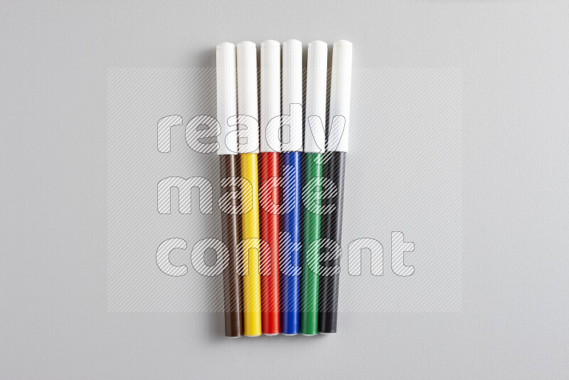 An arrangement of coloring pens in different colors on grey background
