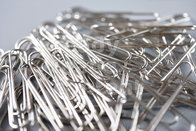 Silver paper clips isolated on a grey background