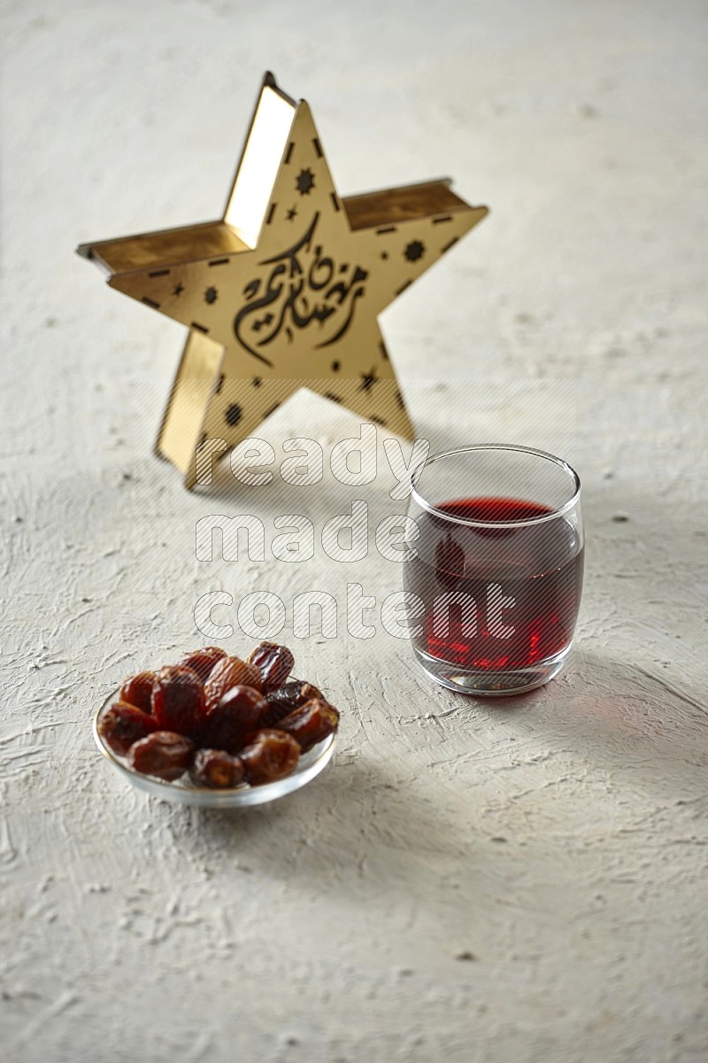 A star lantern with drinks, dates, nuts, prayer beads and quran on textured white background