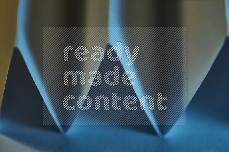 A close-up abstract image showing sharp geometric paper folds in blue gradients and warm tones