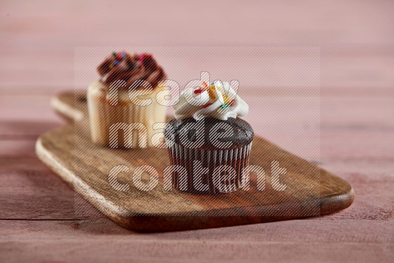 Chocolate mini cupcake topped with cream on a wooden board