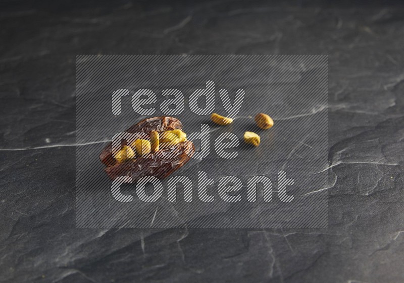 pistachios stuffed madjoul date on a black textured background