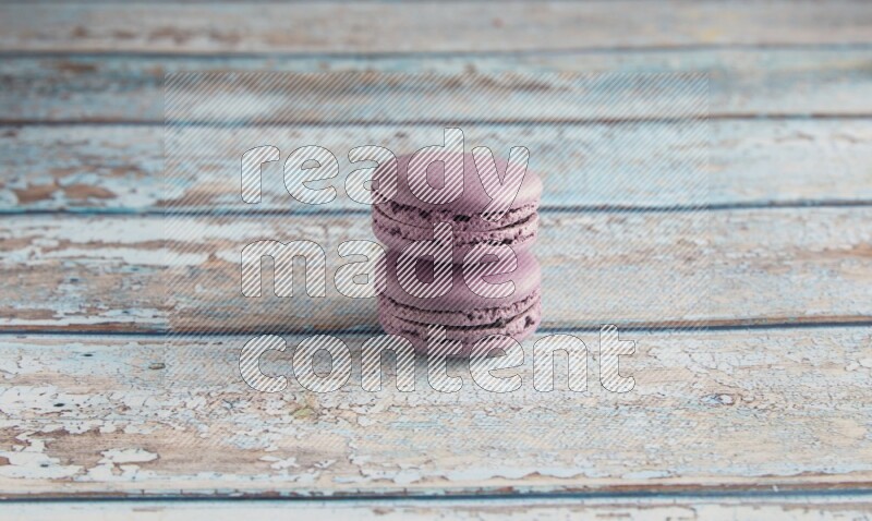 45º Shot of two Purple Blueberry macarons on light blue wooden background