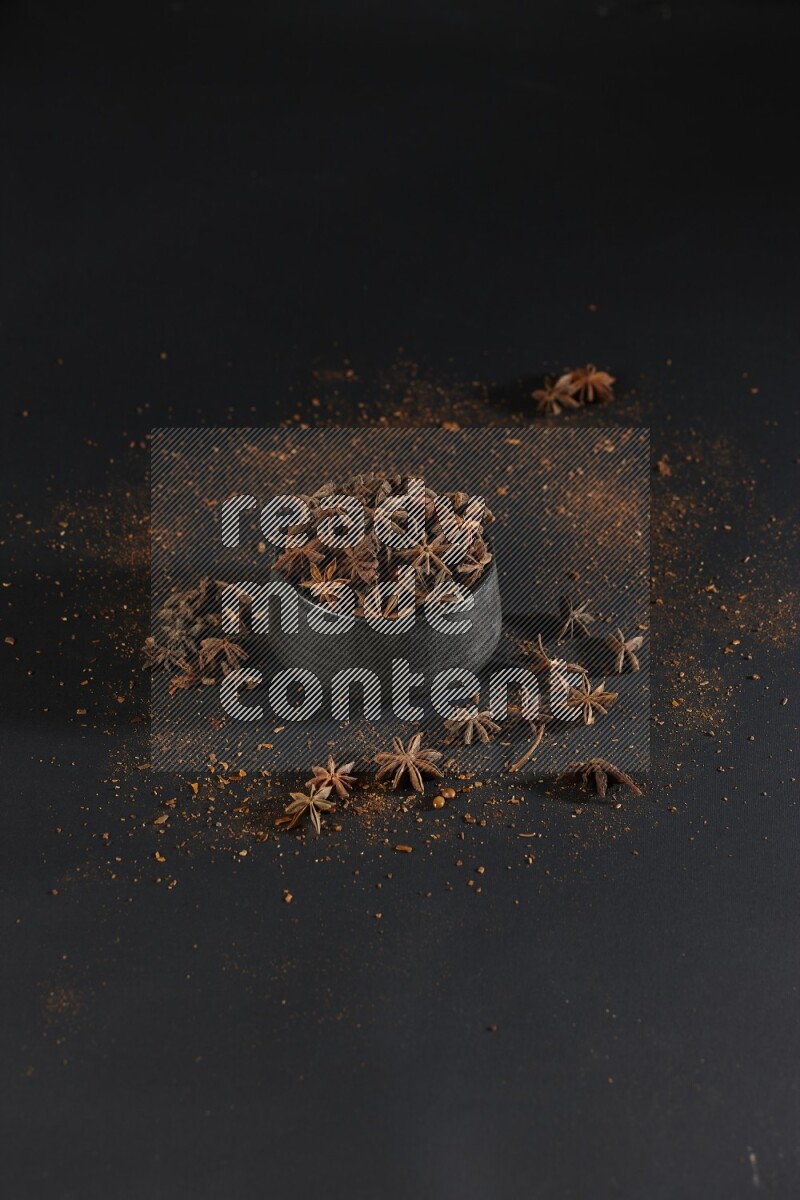 اليانسون النجمي في وعاء أسود مع اليانسون المنثور على خلفية سوداء