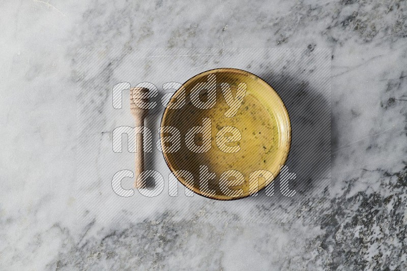Multicolored Pottery Oven Plate with wooden honey handle on the side on grey marble flooring, Top view