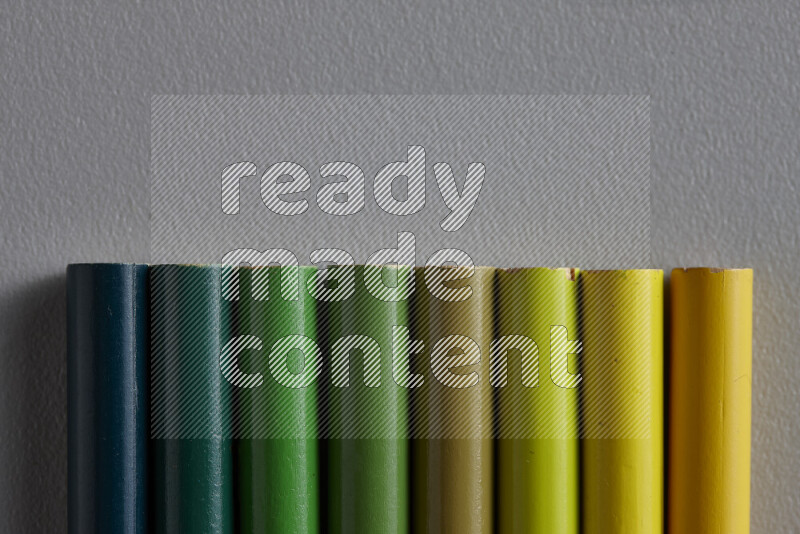 مجموعة من أقلام الرصاص الملونة مرتبة لتعرض تدرجا من الألوان الخضراء علي خلفية رمادية