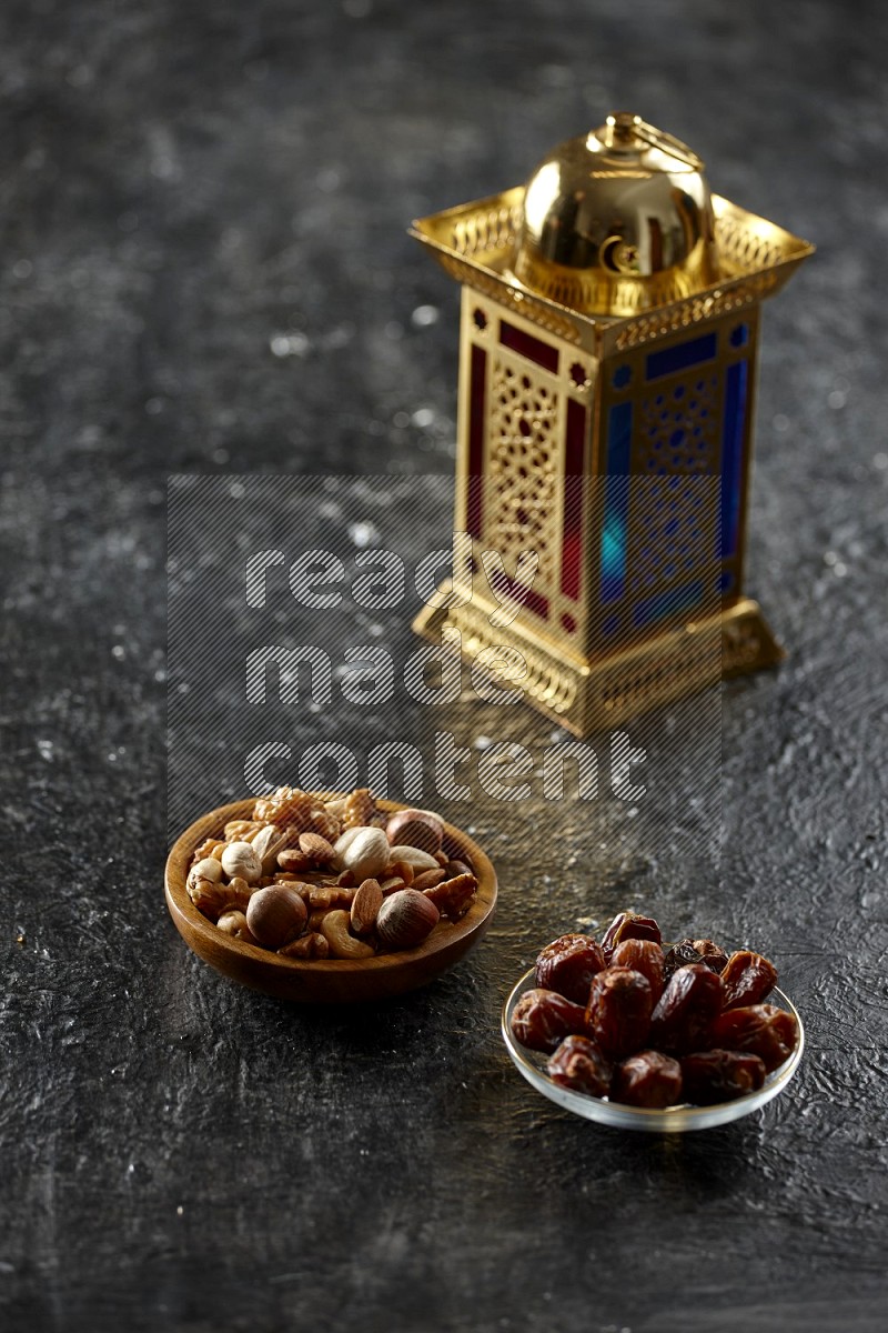 A golden lantern with different drinks, dates, nuts, prayer beads and quran on textured black background