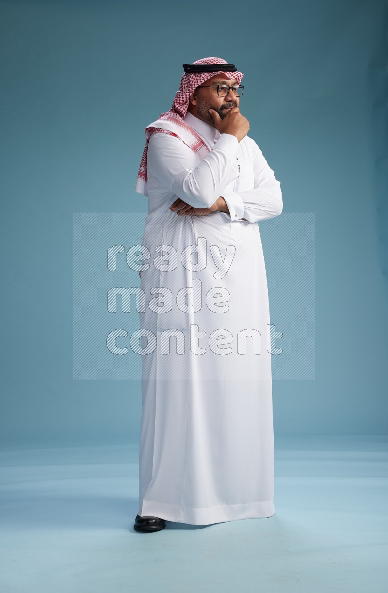 Saudi Man with shimag Standing Interacting with the camera on blue background