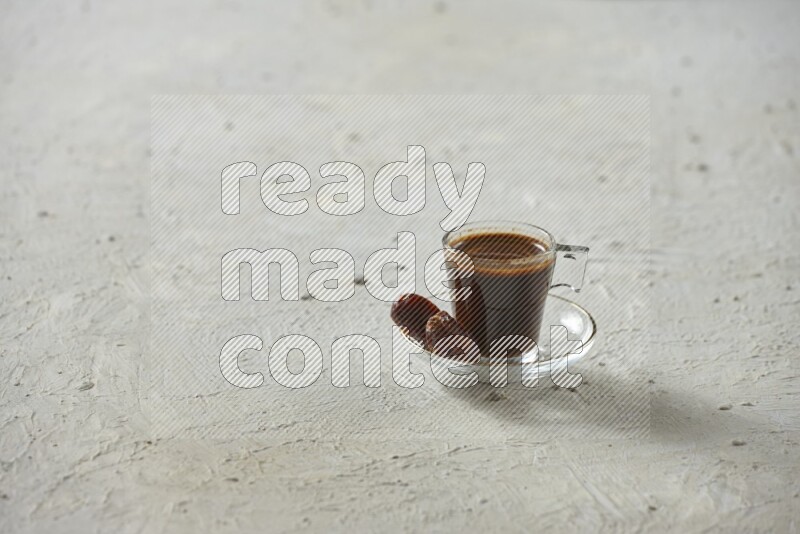 A coffee glass cup with dates and tea on textured white background