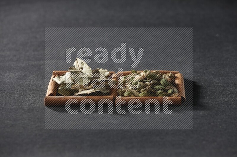 2 squares of cinnamon sticks full of cardamom and bay laurel leaves on black flooring