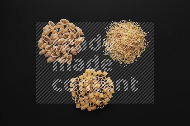 Different pasta types in bunches on black background