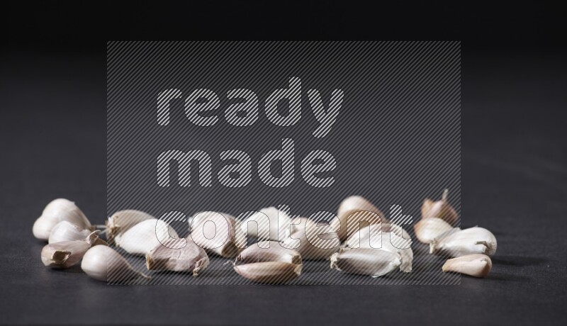 Scattered garlic cloves on a black flooring