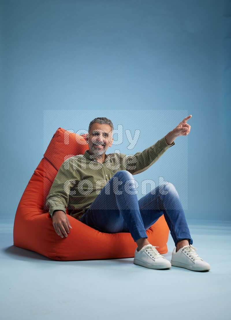 A man sitting on an orange beanbag and interacting with the camera