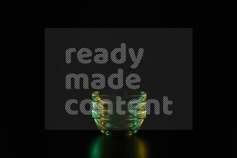 Glassware with rim light in green and yellow against black background