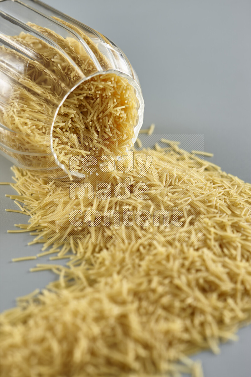 Flipped jar full of raw pasta on light blue background