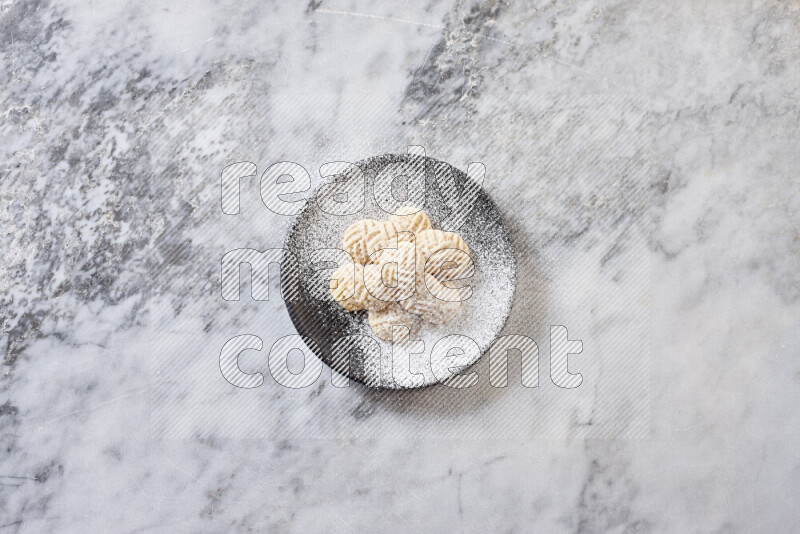 كحك في صحن فخار أسود على خلفية رخام رمادي