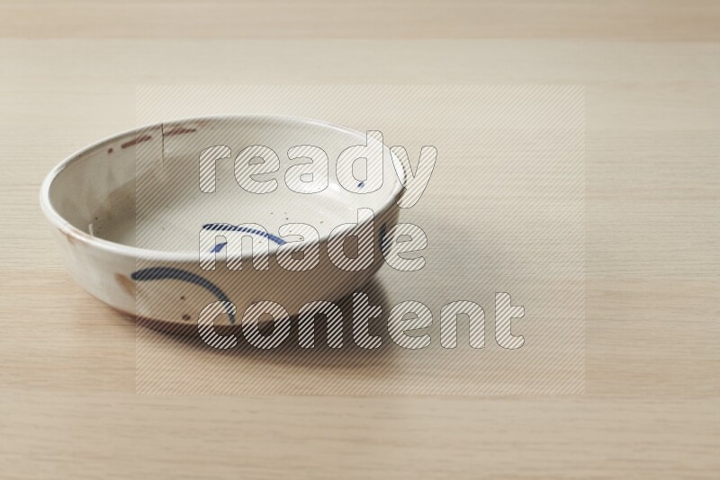 A multicolored pottery bowl on light wooden background
