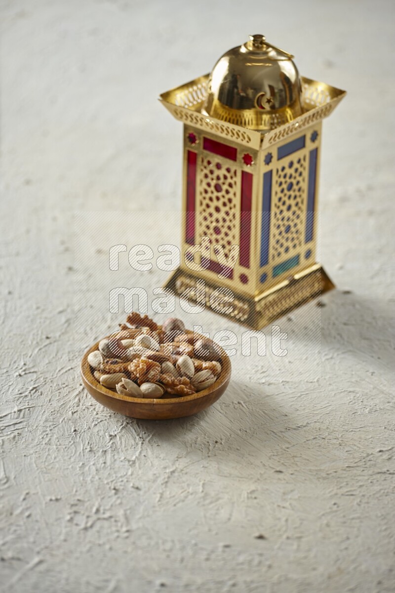 A golden lantern with different drinks, dates, nuts, prayer beads and quran on textured white background