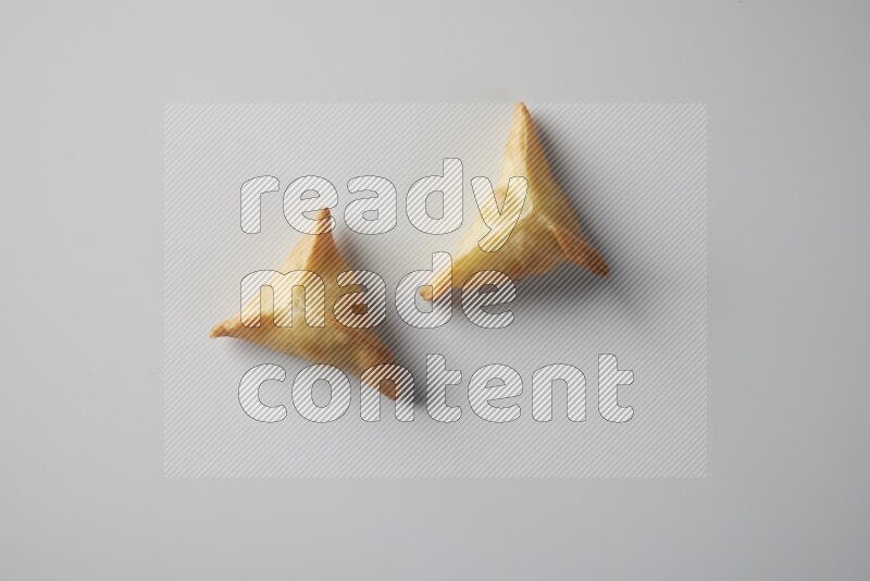 Two fried sambosa from a top angle on a white background