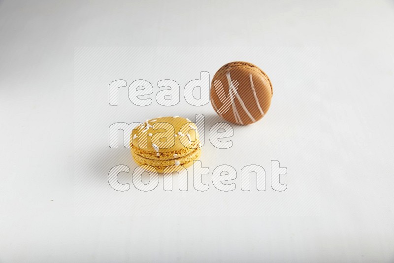 45º Shot of of two assorted Brown Irish Cream, and Yellow Piña Colada macarons on white background
