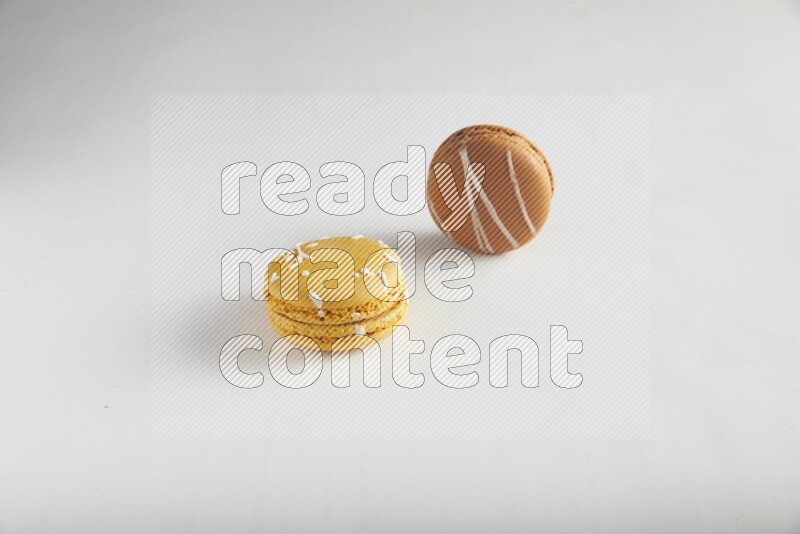 45º Shot of of two assorted Brown Irish Cream, and Yellow Piña Colada macarons on white background