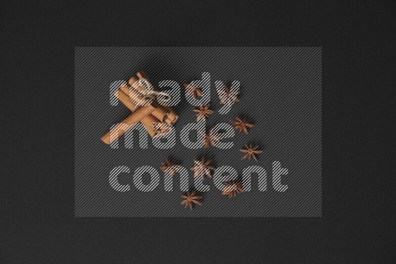 Cinnamon sticks stacked and bounded and star anise on black background