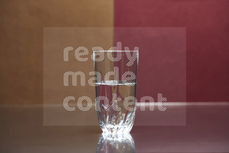 The image features a clear glassware filled with water, set against brown and dark red background