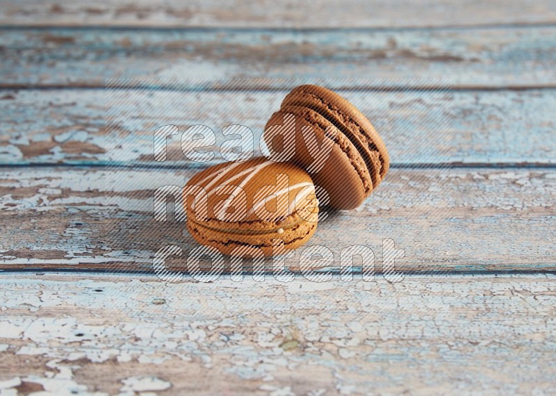 45º Shot of of two assorted Brown Irish Cream, and Brown Coffee macarons on light blue background