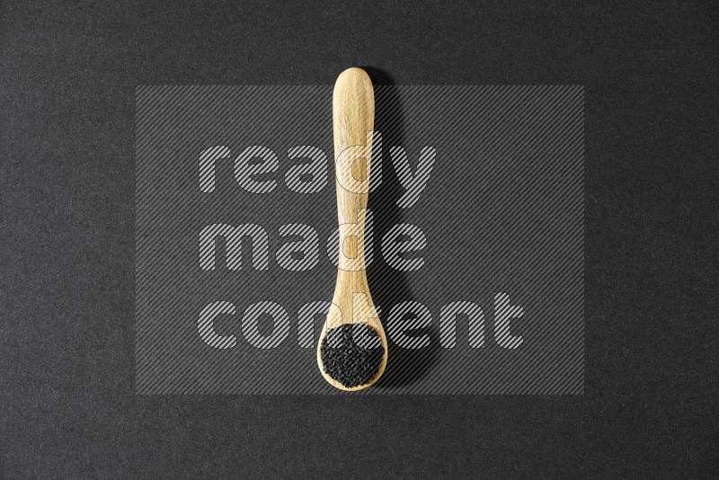 A wooden spoon full of black seeds on a black flooring in different angles