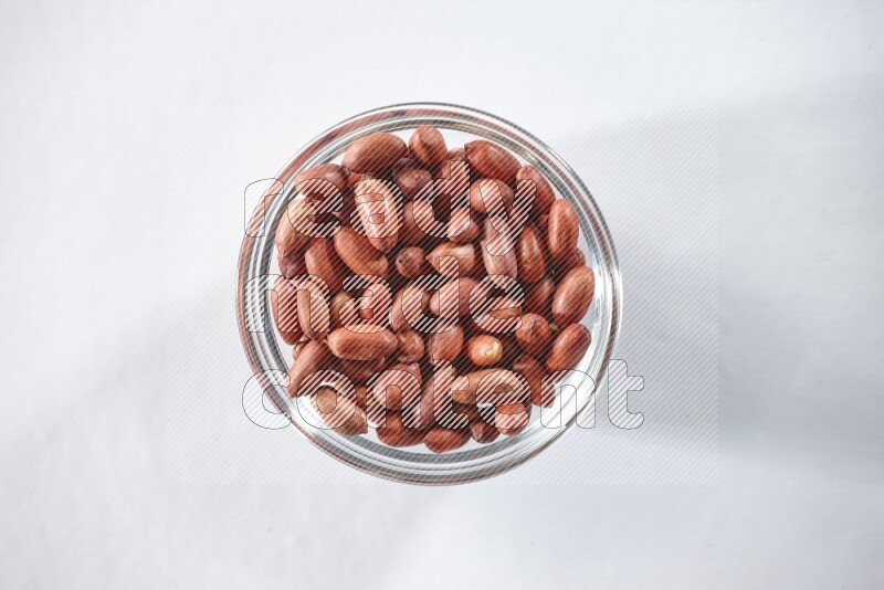 A glass bowl full of red skin peanuts on a white background in different angles