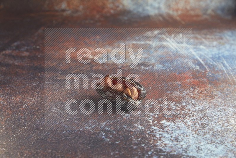 one hazelnut stuffed madjoul date on a rustic reddish background