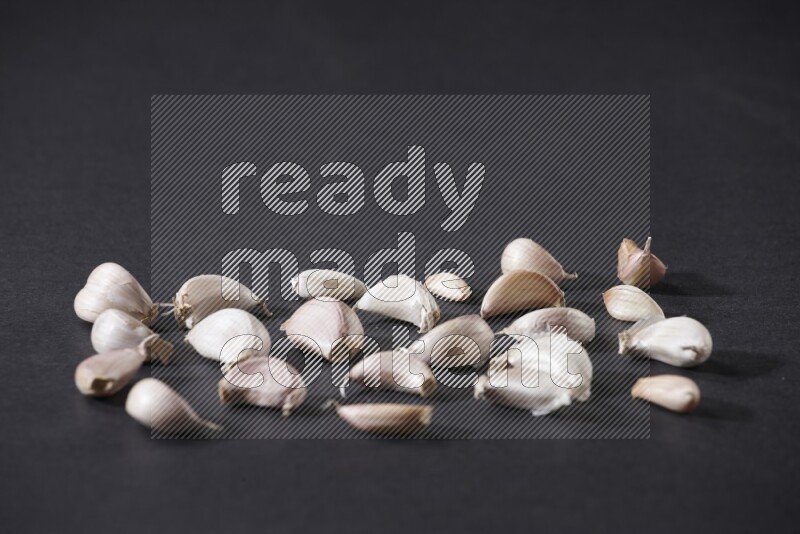 Scattered garlic cloves on a black flooring