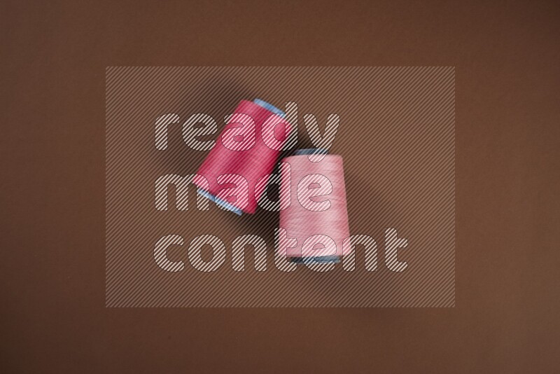 مجموعة من أدوات الخياطة والتفصيل زهرية اللون على خلفية بنية