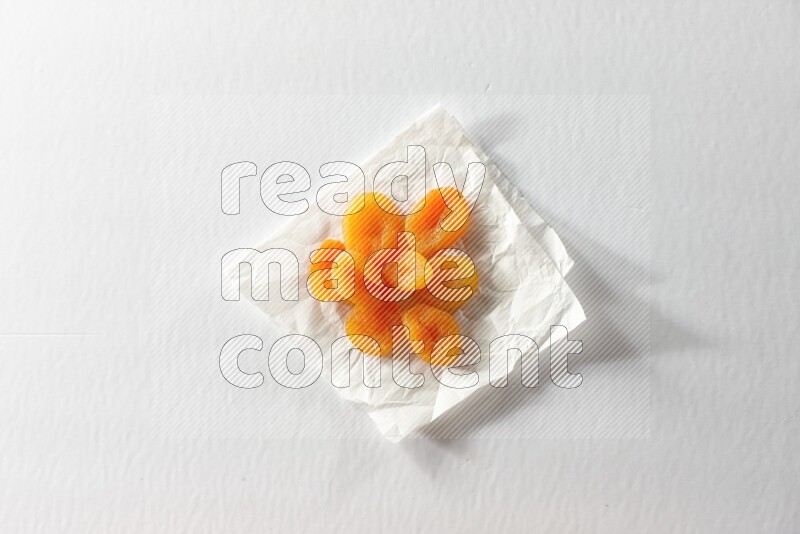 Dried apricots on a crumpled piece of paper on a white background in different angles