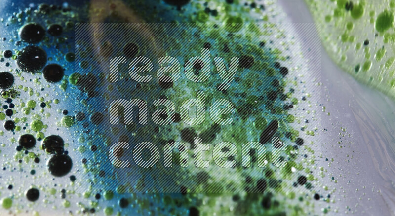 لقطات مقربة لقطرات ألوان مائية خضراء وزرقاء على سطح الزيت على خلفية بيضاء