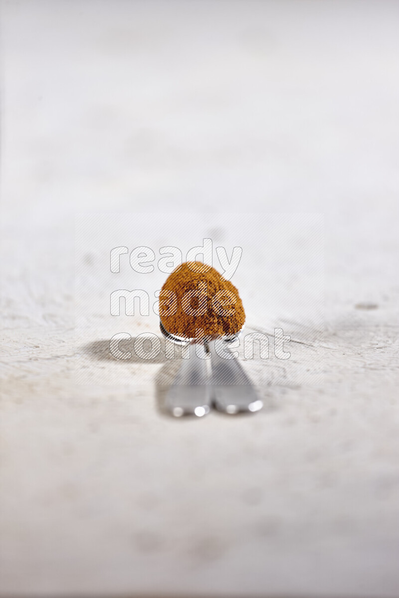 Two metal spoons full of ground paprika powder on white background