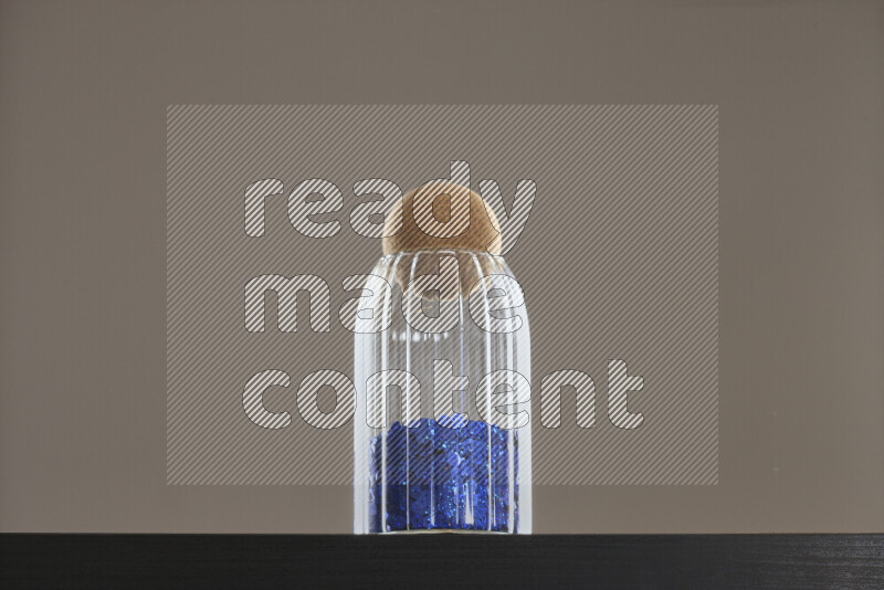 Sequins in a glass jar on black background