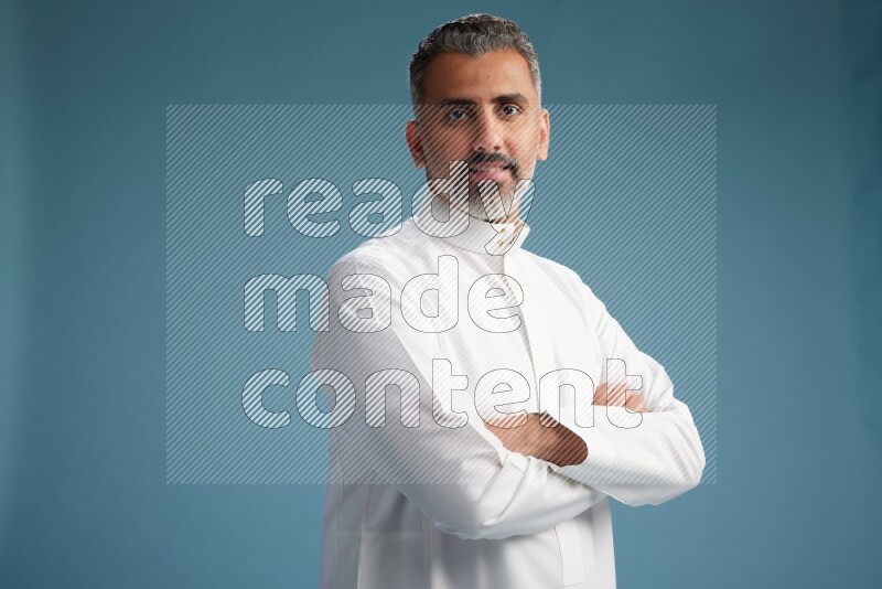 Saudi man waring thob posing to the camera on blue background