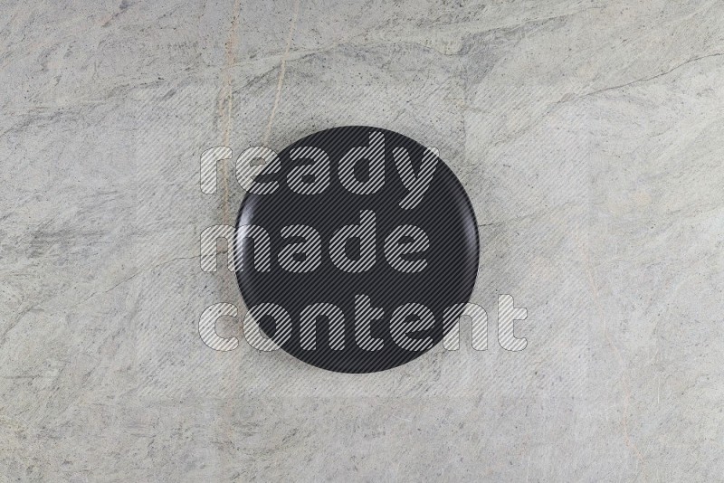 Top View Shot Of A Black Ceramic Circular Plate On Grey Marble Flooring