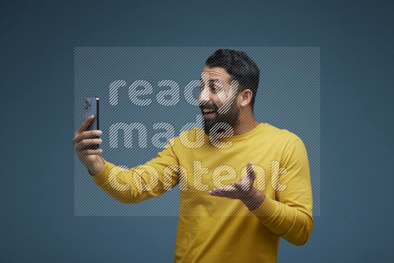 Man Taking a Selfie  in a blue background wearing a yellow shirt