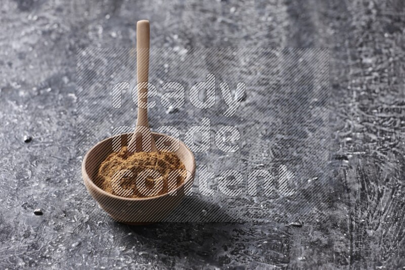 Wooden bowl full of cinnamon powder with a wooden spoon on a textured black background in different angles