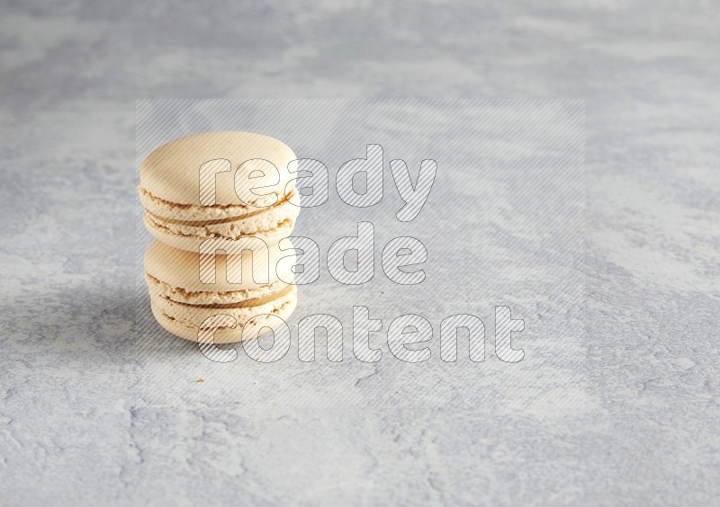 45º Shot of two white marbleCaramel fleur de sel macarons  on white  marble background