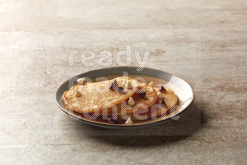 Three stacked chocolate chips pancakes in a bicolor plate on beige background